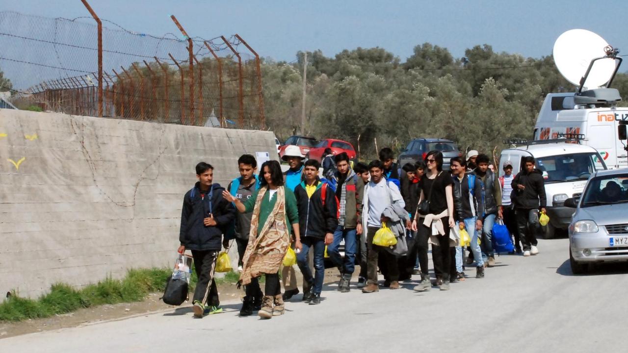 Flüchtlinge gehen an der Mauer des Auffanglagers "Moria" auf der griechischen Insel Lesbos in der Hafenstadt Mitilini entlang. Flüchtlinge gehen an der Mauer des Auffanglagers "Moria" auf der griechischen Insel Lesbos in der Hafenstadt Mitilini entlang.