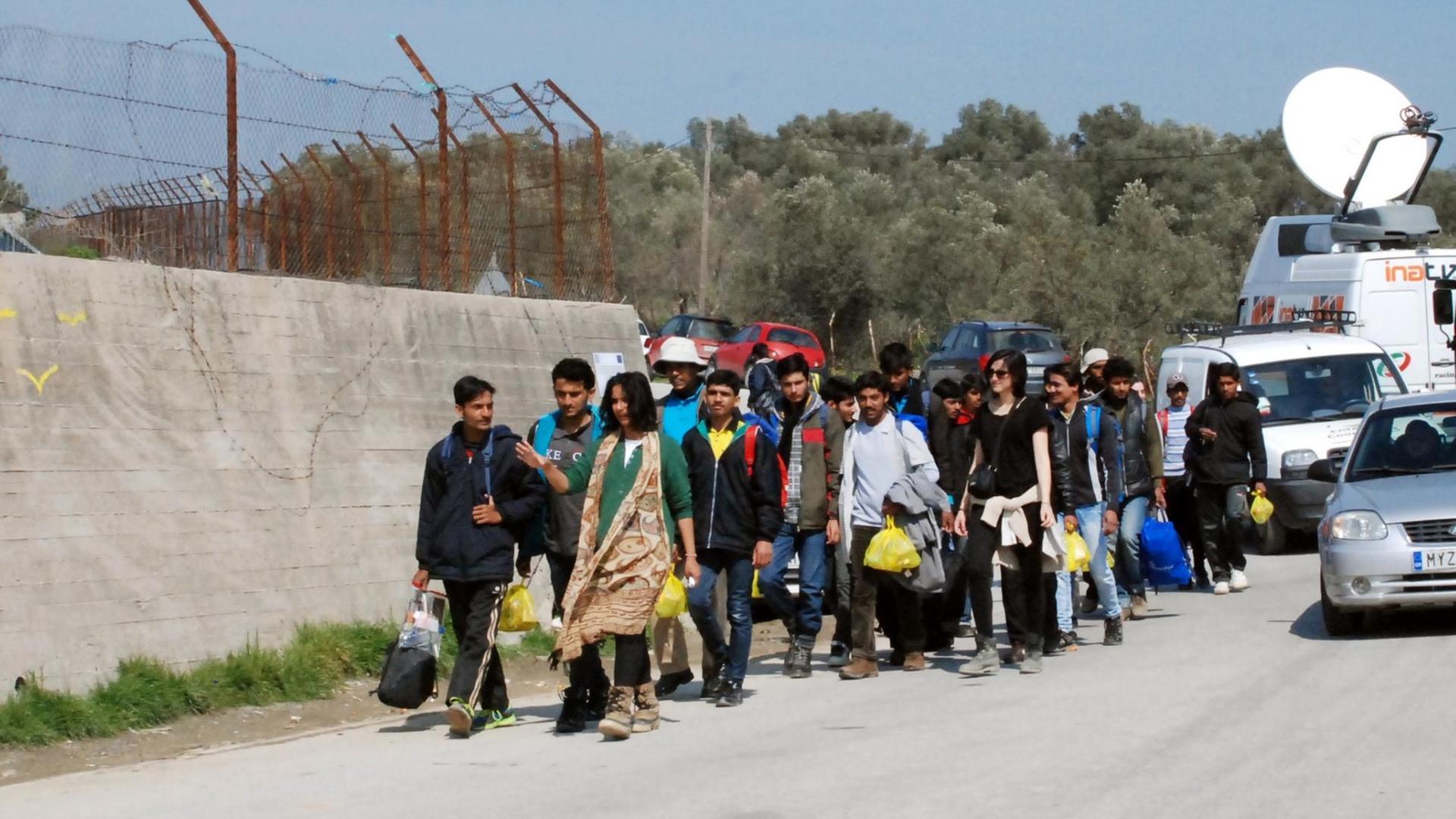 Flüchtlinge gehen an der Mauer des Auffanglagers "Moria" auf der griechischen Insel Lesbos in der Hafenstadt Mitilini entlang. Flüchtlinge gehen an der Mauer des Auffanglagers "Moria" auf der griechischen Insel Lesbos in der Hafenstadt Mitilini entlang.