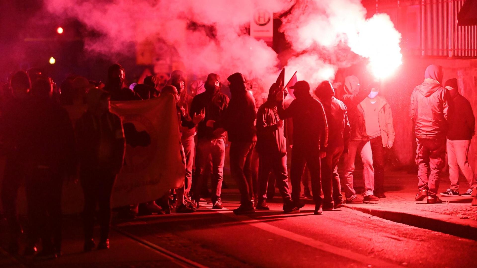 Teilnehmer einer Demonstration ziehen mit roten Pyro-Fackeln durch den Stadtteil Connewitz.