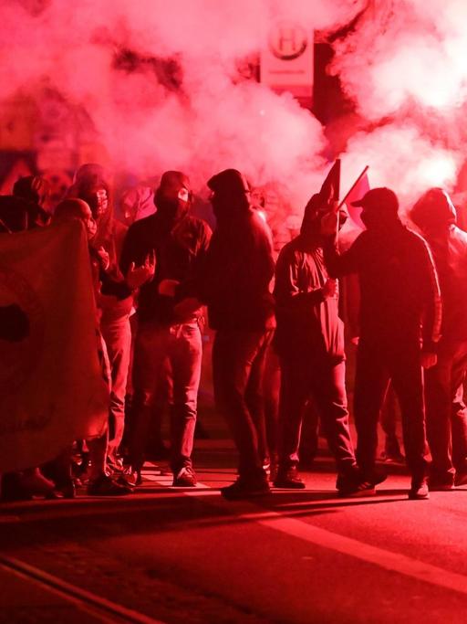 Teilnehmer einer Demonstration ziehen mit roten Pyro-Fackeln durch den Stadtteil Connewitz.