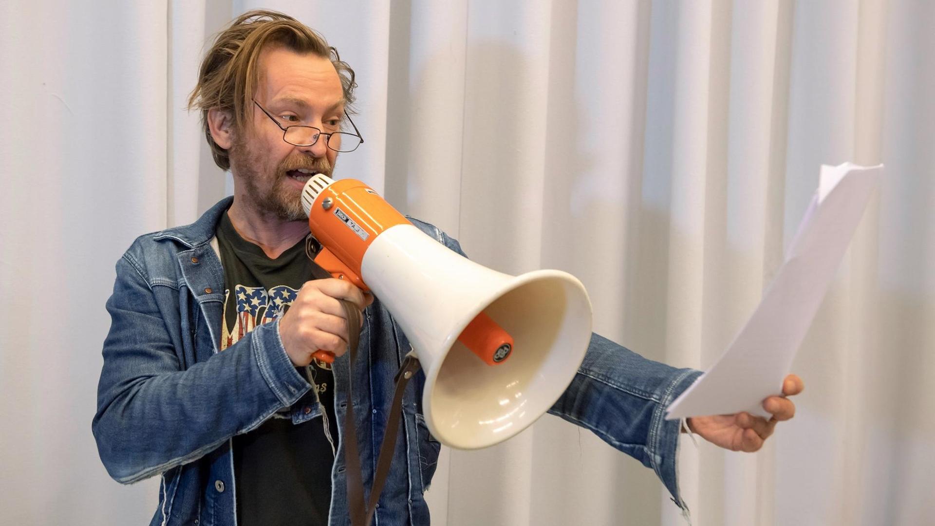 Ein Mann mit Megafon liest etwas vor. Ein Mann mit Megafon liest etwas vor.