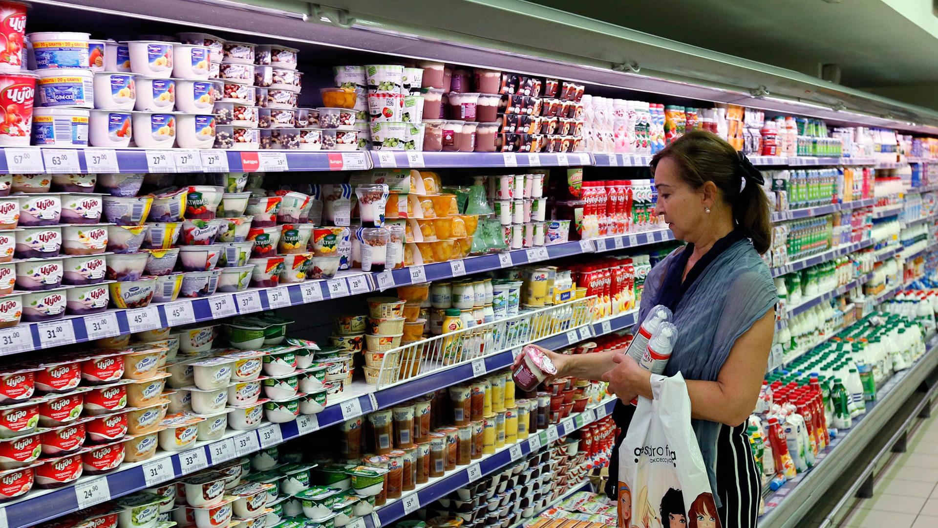 Eine Frau steht in einem Moskauer Supermarkt vor einer Kühltheke mit Milchprodukten.