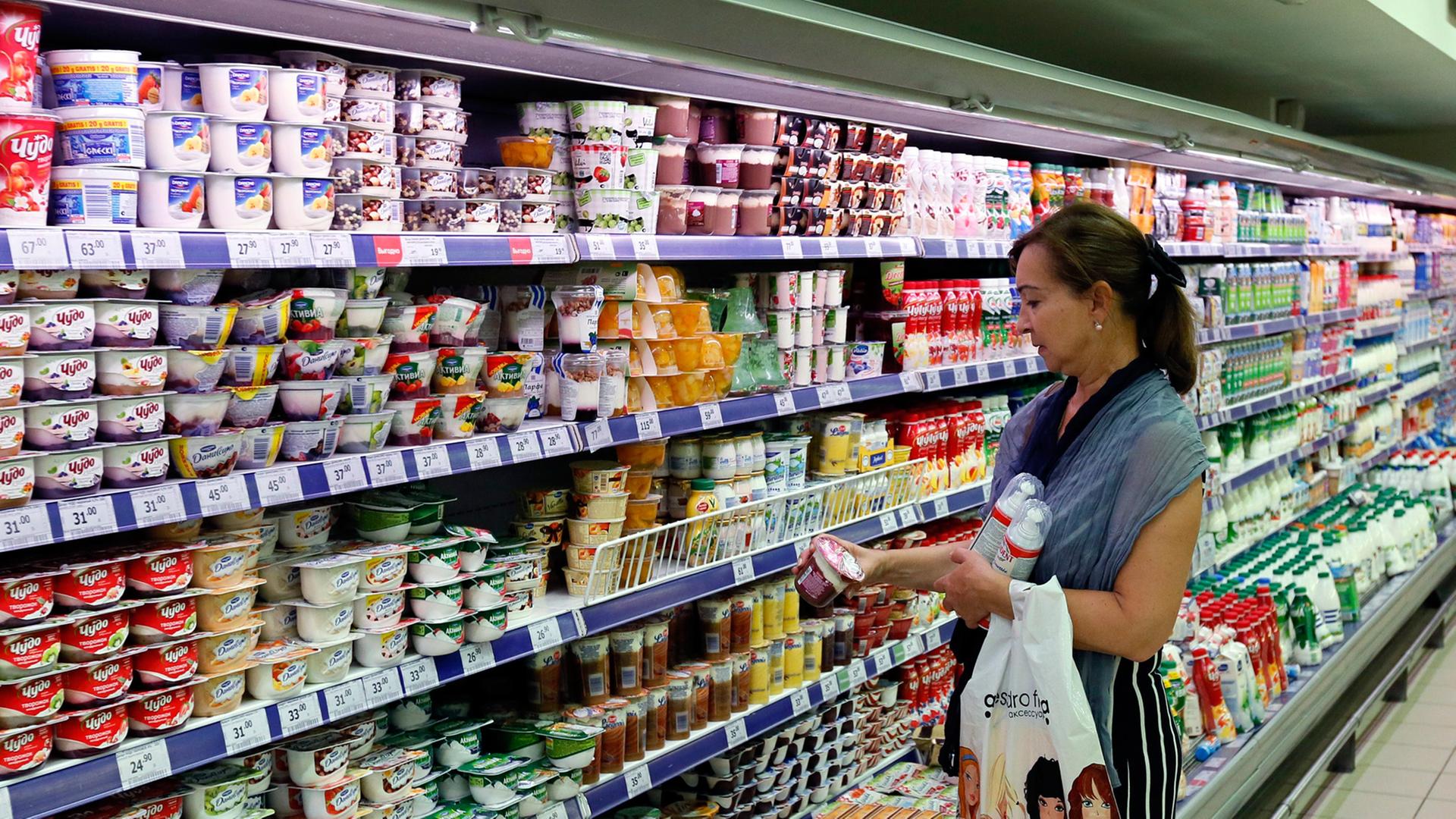 Eine Frau steht in einem Moskauer Supermarkt vor einer Kühltheke mit Milchprodukten. Eine Frau steht in einem Moskauer Supermarkt vor einer Kühltheke mit Milchprodukten.