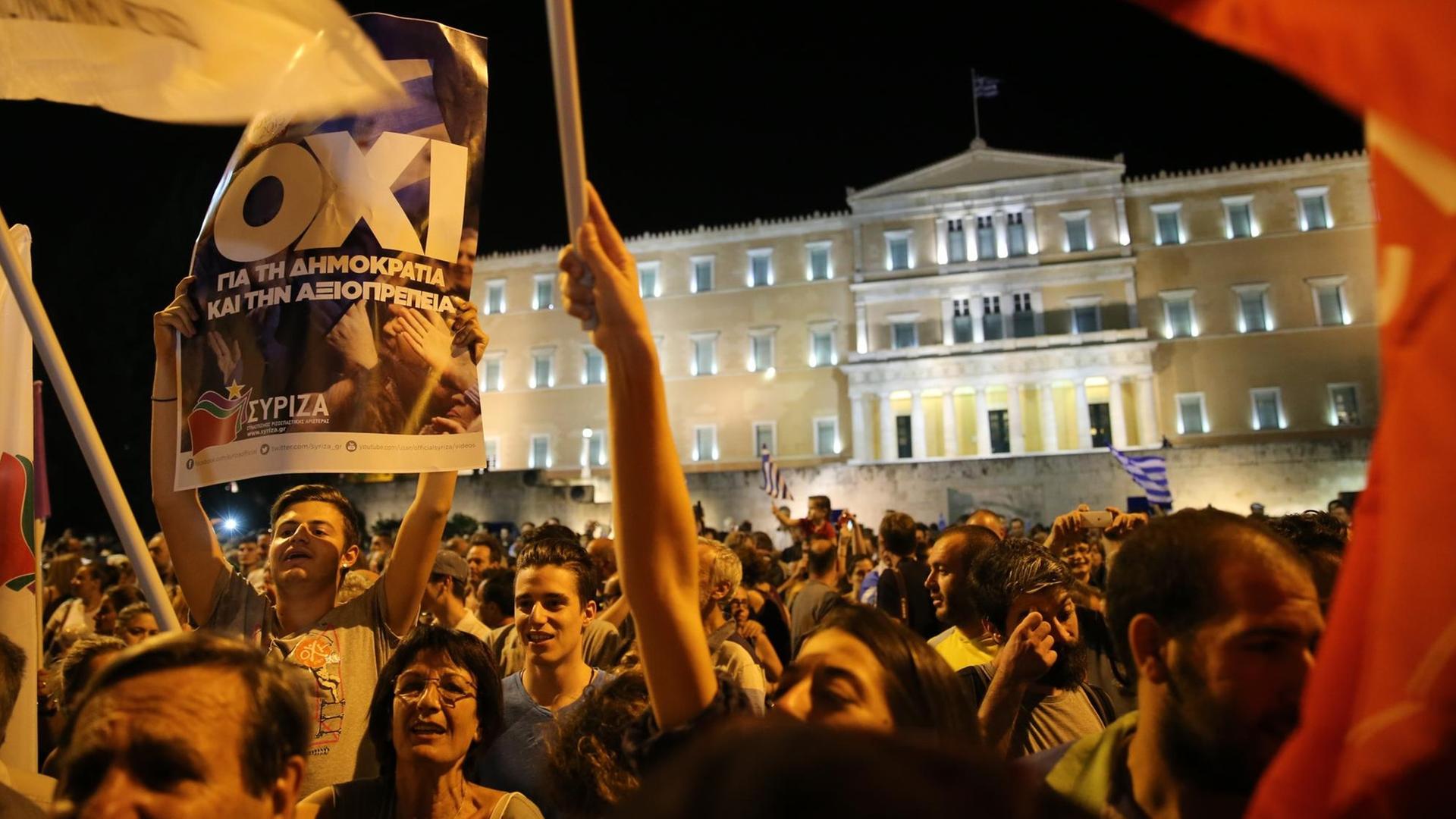 Demonstranten stehen mit griechischen Fahnen und "Oxi"-Plakaten vor dem angestrahlten Parlament in Athen. Demonstranten stehen mit griechischen Fahnen und "Oxi"-Plakaten vor dem angestrahlten Parlament in Athen.