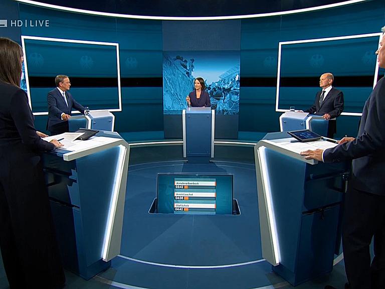 Die Kanzlerkandidaten Armin Laschet, Annalena Baerbock und Olaf Scholz stehen in einem Fernsehstudio. Vorne die Moderatoren Pinar Atalay und Peter Kloeppel.