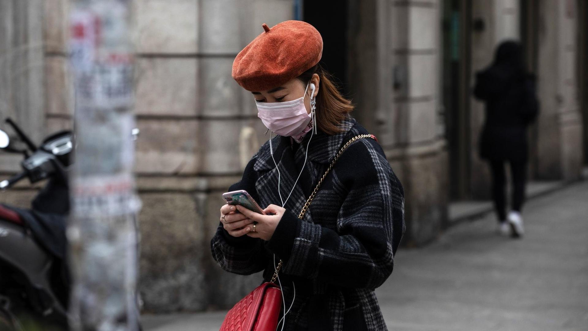 Eine Frau mit Atemmaske benutzt ihr Smartphone. Eine Frau mit Atemmaske benutzt ihr Smartphone.