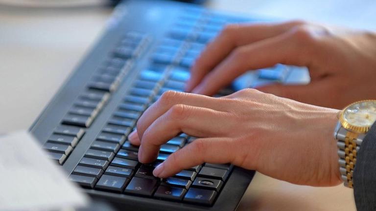 Eine Frau arbeitet an einer Computer-Tastatur. Eine Frau arbeitet an einer Computer-Tastatur.