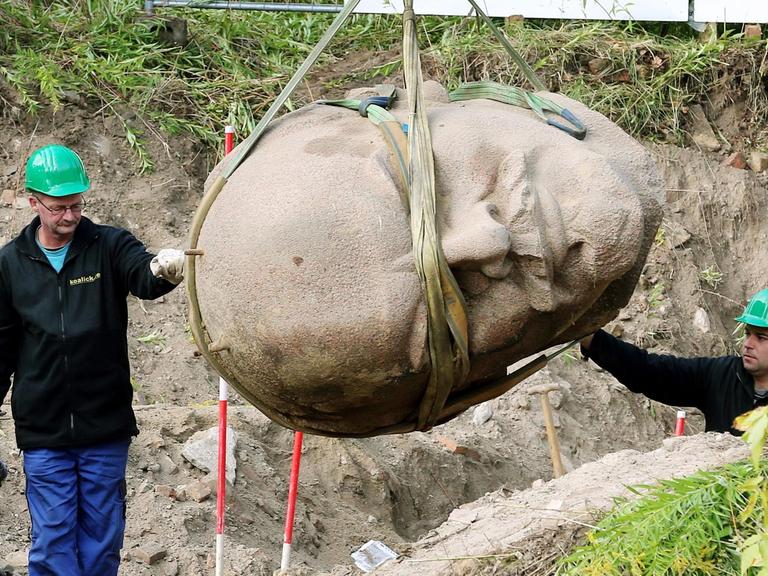 Arbeiter einer Spezialfirma sichern in einem Waldstück am Müggelsee in Berlin den an einem Kran hängenden Kopf einer Lenin-Statue.