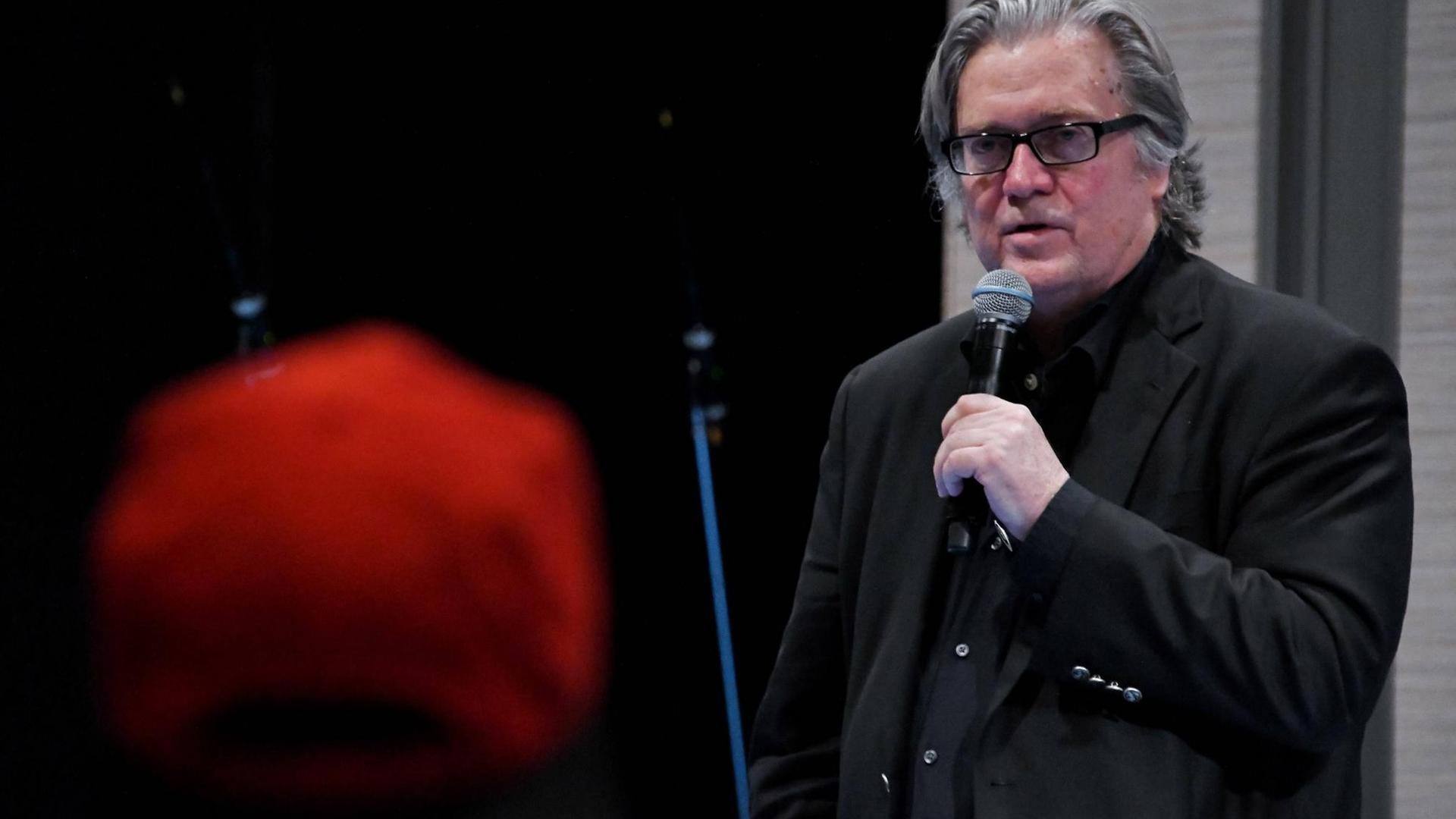 Steve Bannon mit Brille und einem Mikrofon in der Hand Steve Bannon mit Brille und einem Mikrofon in der Hand