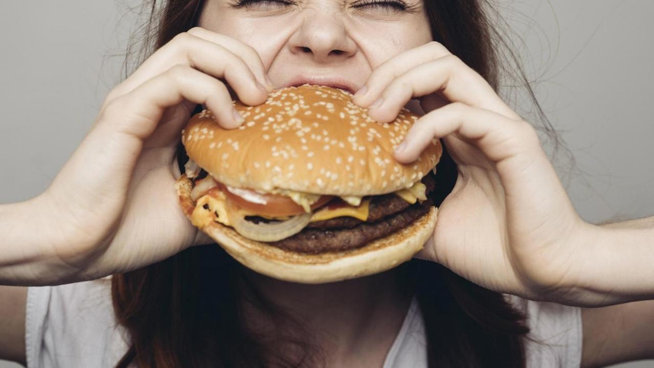 Eine Frau beißt in einen Cheeseburger. Eine Frau beißt in einen Cheeseburger.