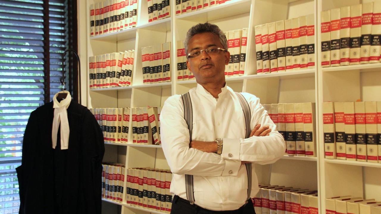 Richter Sajan Poovayya in seinem Büro vor einer Bücherwand in weißem Hemd mit Hosenträgern. Richter Sajan Poovayya in seinem Büro vor einer Bücherwand in weißem Hemd mit Hosenträgern.