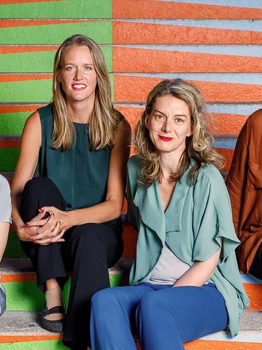 Die vier Musikerinnen des Mondrian Ense´mbles sitzen vor einer bunten, grafisch gestalteten Wand