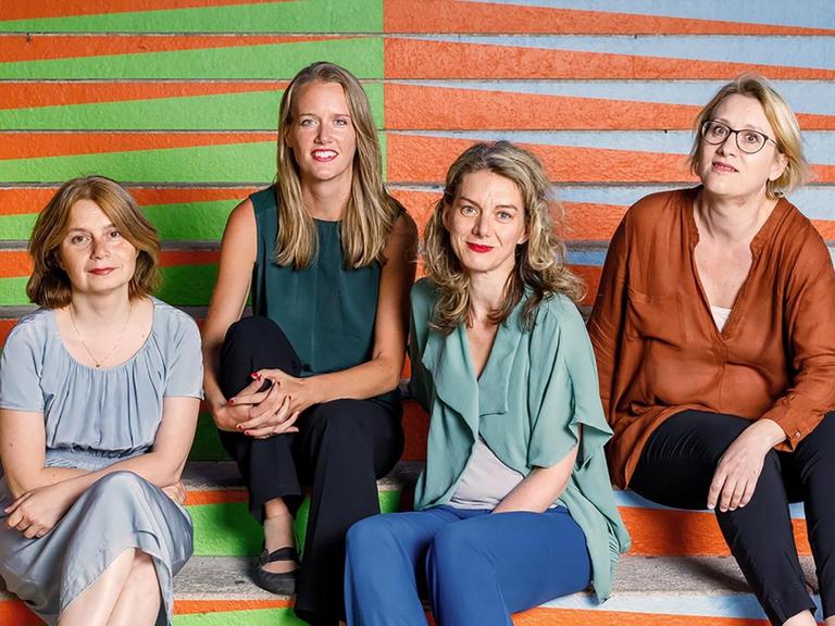 Die vier Musikerinnen des Mondrian Ense´mbles sitzen vor einer bunten, grafisch gestalteten Wand
