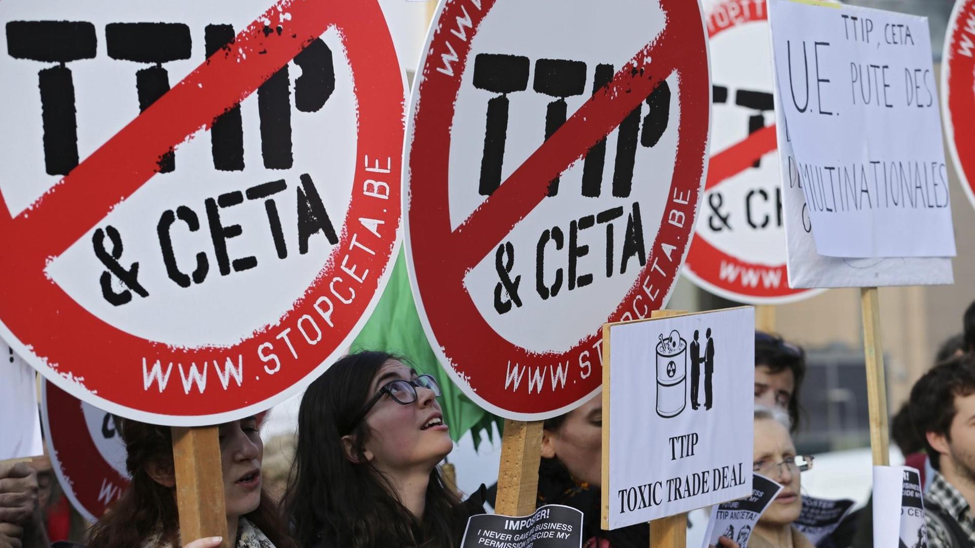 Demonstranten mit Schildern, auf denen die Wörter TTIP und CETA durchgestrichen sind