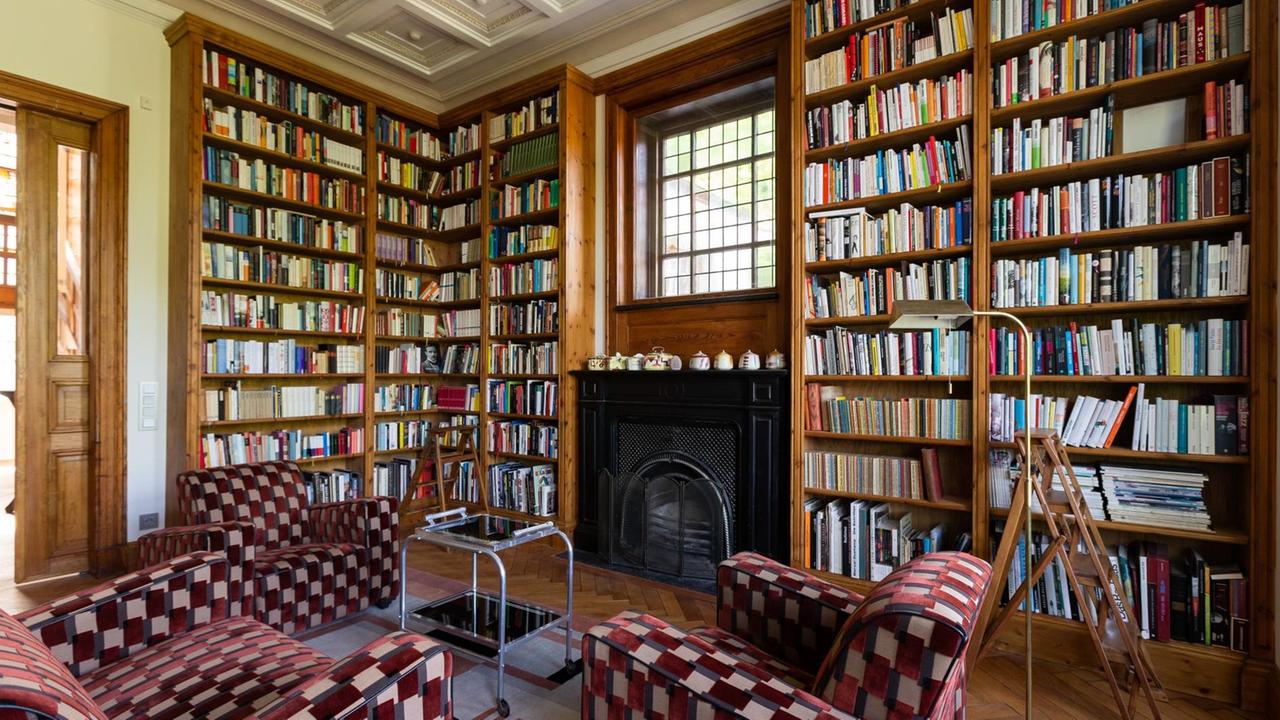 Einblick in die "Villa Willemsen": Reich gefüllte Buchregale vor denen eine Gruppe Sitzgelegenheit zum gemütlichen Lesen einlädt.