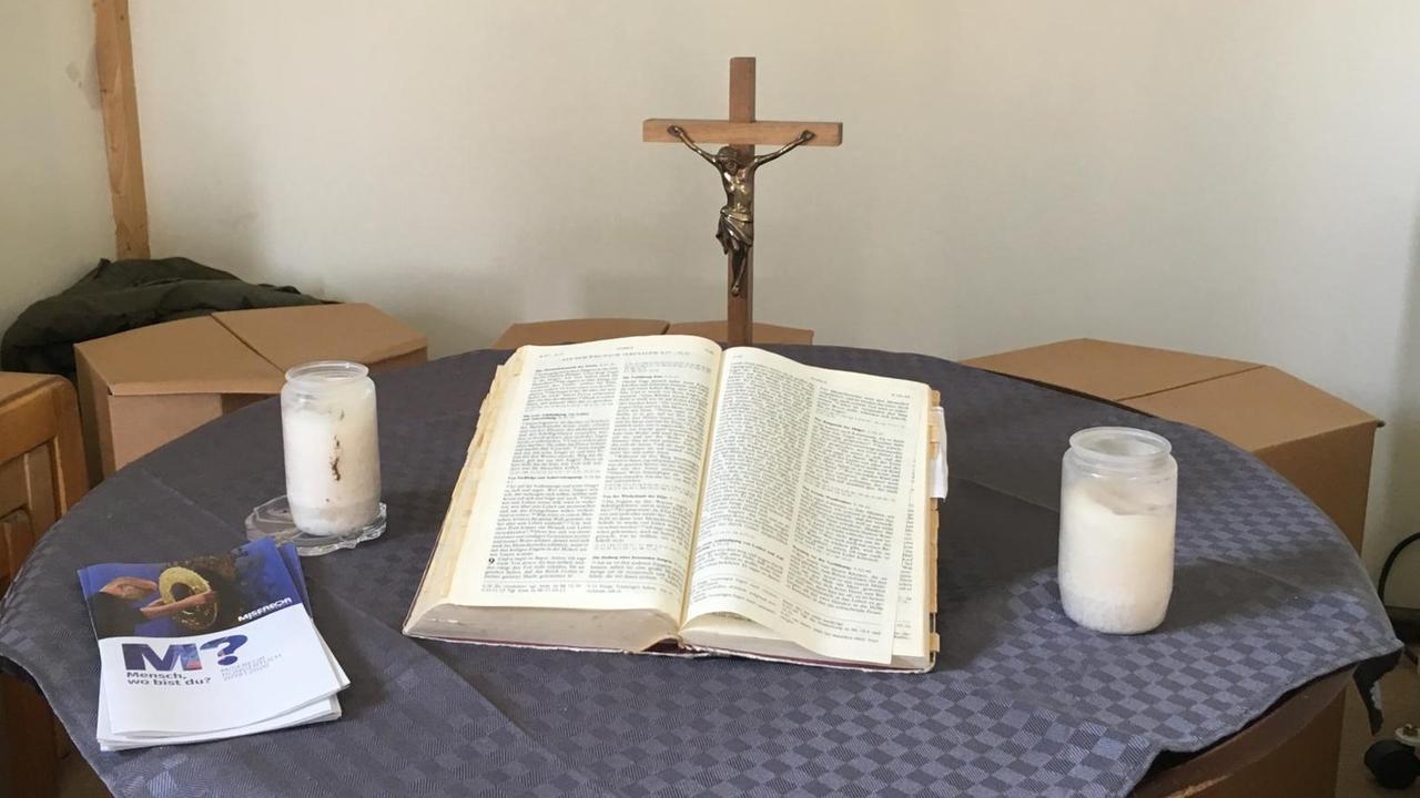 Ein Tisch mit Kreuz, einer Bibel und Kerzen dient im mobilen Andachtsraum des Bauwagens als liturgischer Mittelpunkt.