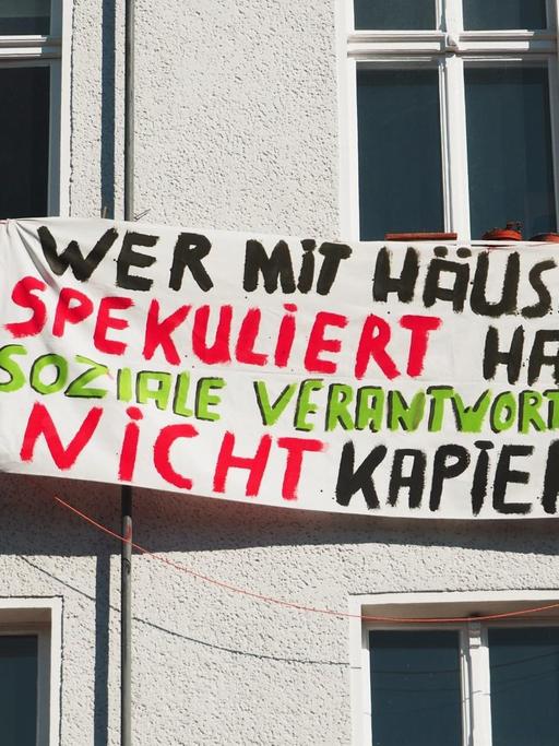 Wer mit Häusern spekuliert hat soziale Verantwortung nicht kapiert!" steht auf einem Transparent an einer Hausfassade in Berlin im Bezirk Schöneberg am 19.03.2015. Foto: Wolfram Steinberg/dpa.