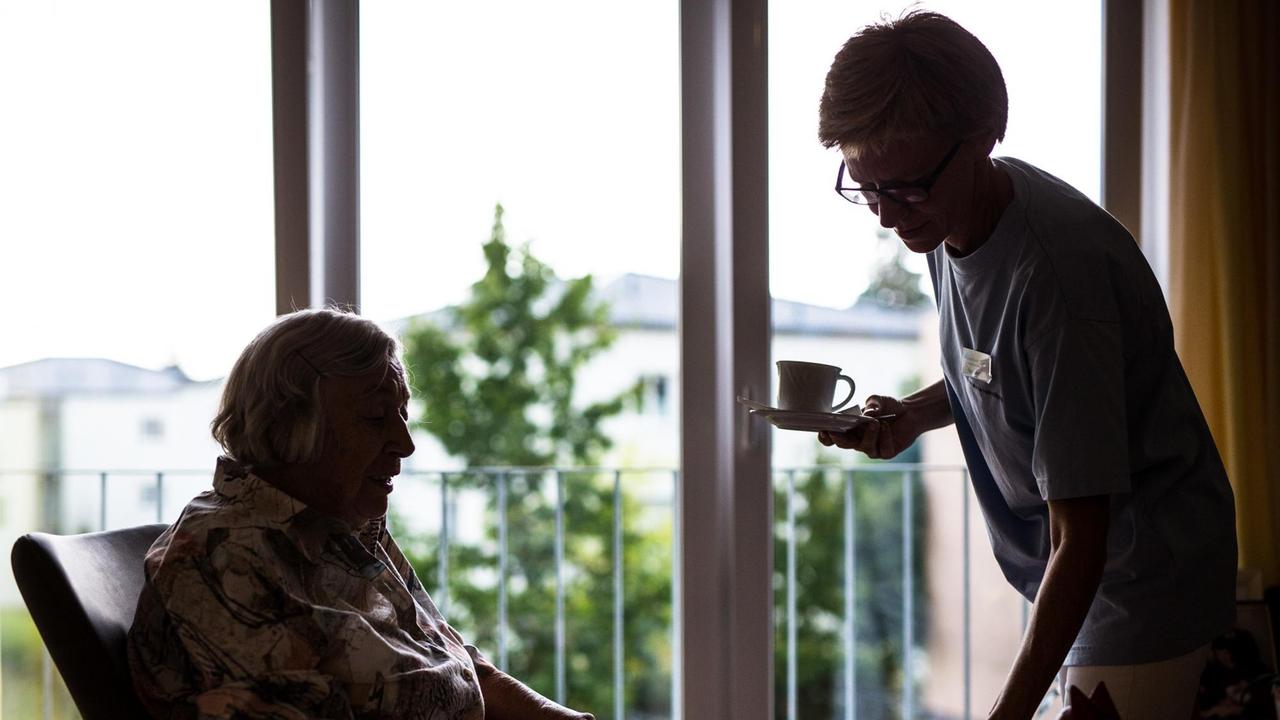 23.08.2018, Baden-Württemberg, Stuttgart: Eine Pflegekraft kümmert sich in einem Pflegeheim um eine ältere Dame und bringt ihr Kaffee und Kuchen. 23.08.2018, Baden-Württemberg, Stuttgart: Eine Pflegekraft kümmert sich in einem Pflegeheim um eine ältere Dame und bringt ihr Kaffee und Kuchen.