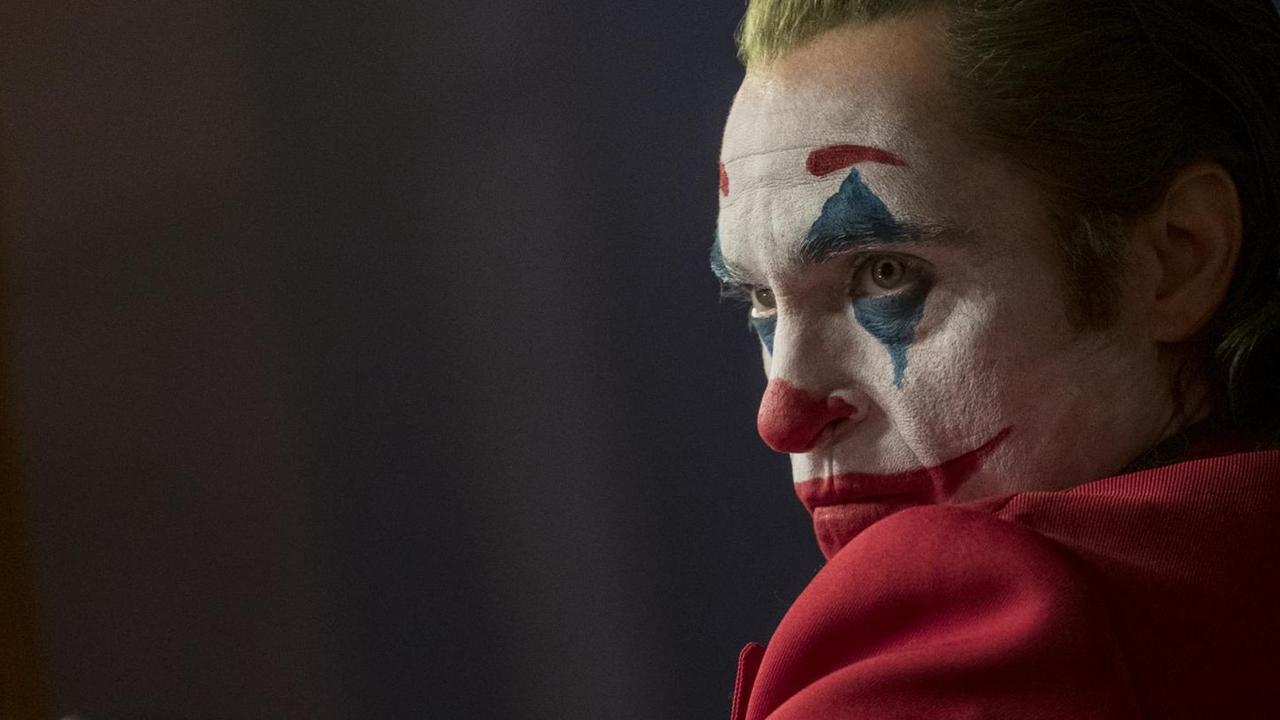 Joaquin Phoenix schaut über die linke Schulter, mit Clownsschminke im Gesicht und grünen Haaren. Joaquin Phoenix schaut über die linke Schulter, mit Clownsschminke im Gesicht und grünen Haaren.