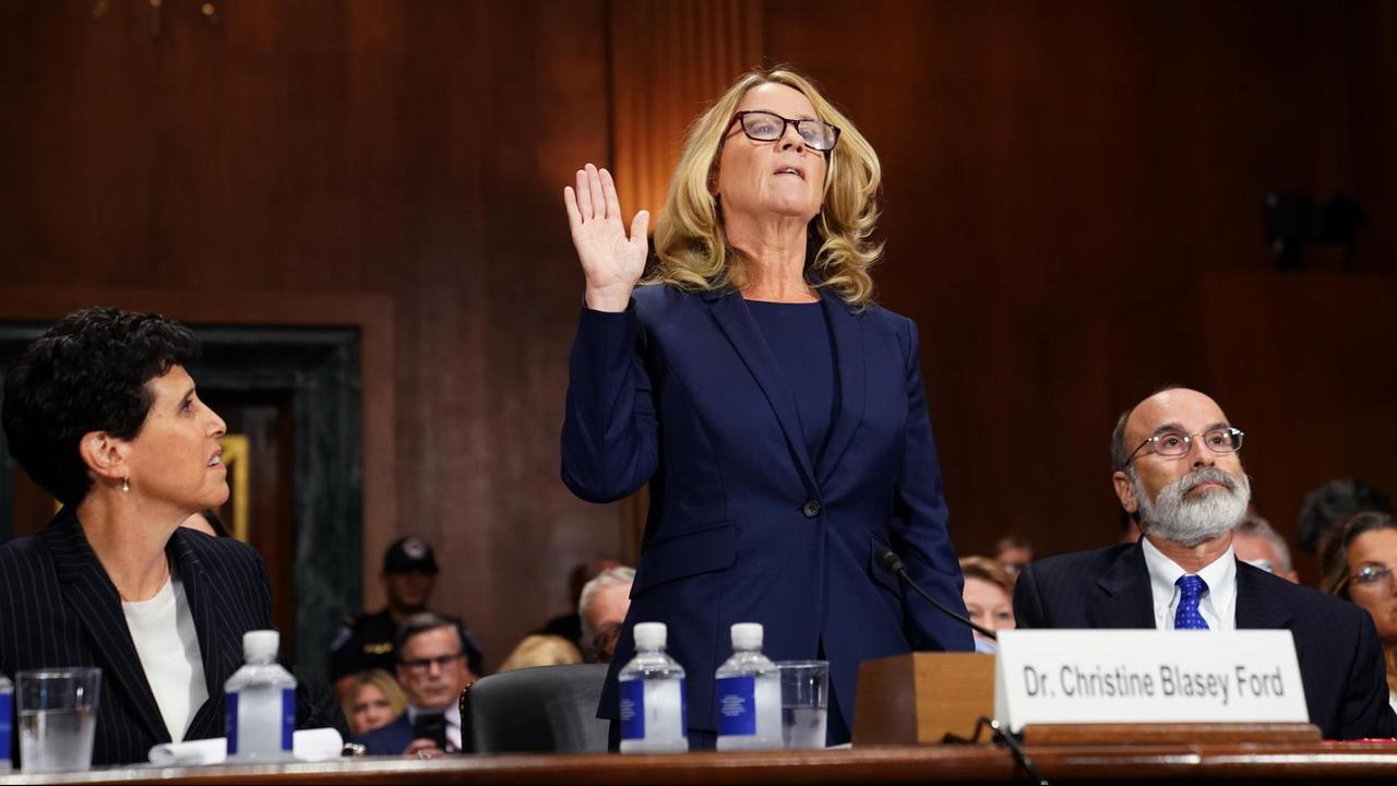 Das Bild zeigt Christine Blasey Ford vor ihrer Anhörung im US-Senat. Sie hebt die rechte Hand zum Schwur. 