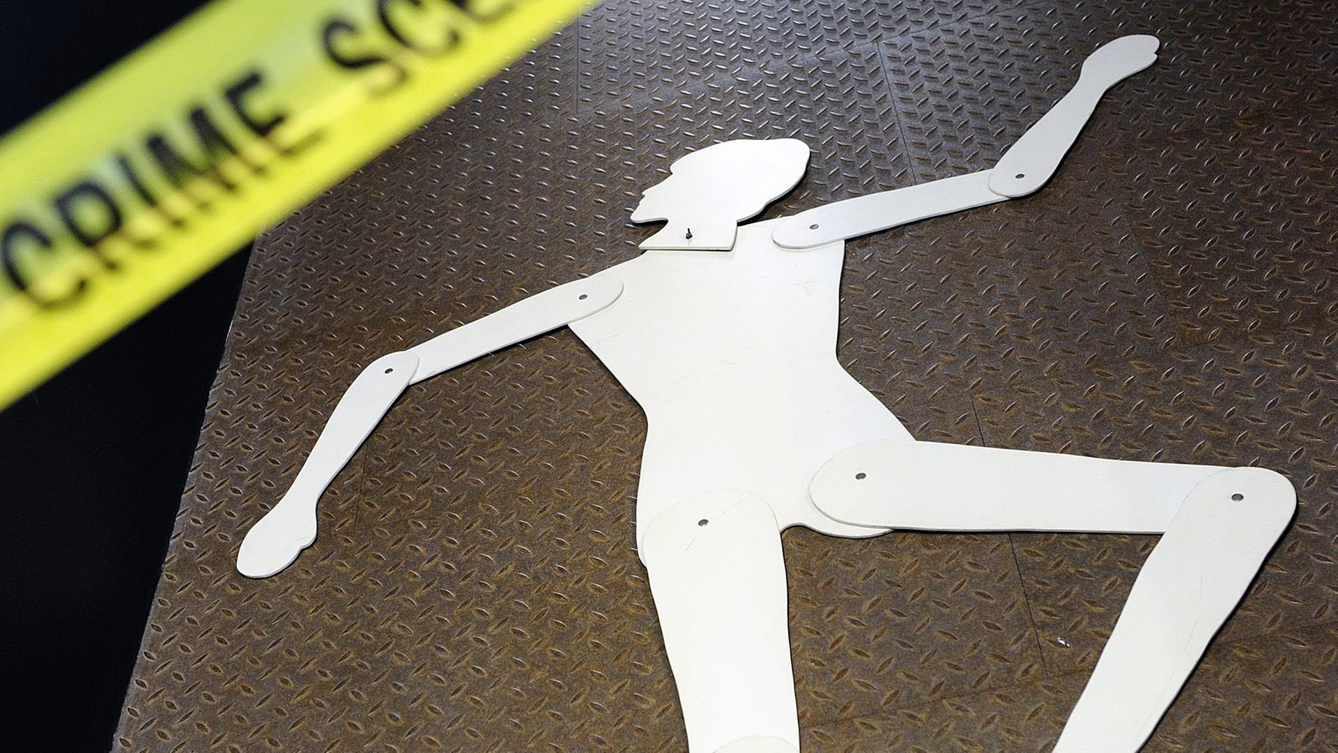 Das Bild zeigt die Silhouette einer Frau an einem Tatort, der durch ein gelbes Band mit der Schrift "Crime Scene" abgetrennt ist. Das Bild zeigt die Silhouette einer Frau an einem Tatort, der durch ein gelbes Band mit der Schrift "Crime Scene" abgetrennt ist.