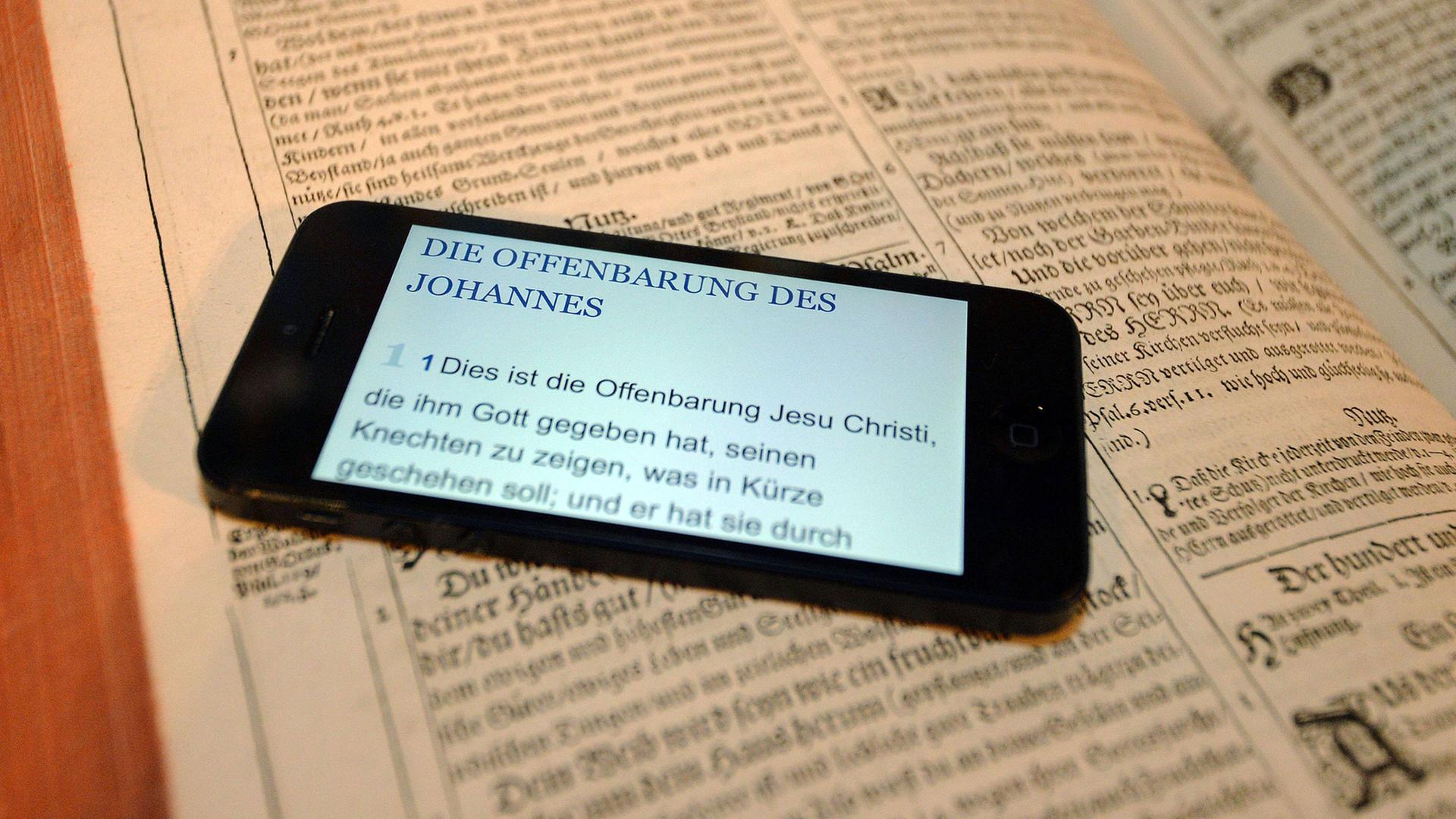 Ein Smartphone mit einem Text aus der Offenbarung des Johannes liegt am 21.10.2014 auf einer Bibel. Ein Smartphone mit einem Text aus der Offenbarung des Johannes liegt am 21.10.2014 auf einer Bibel.
