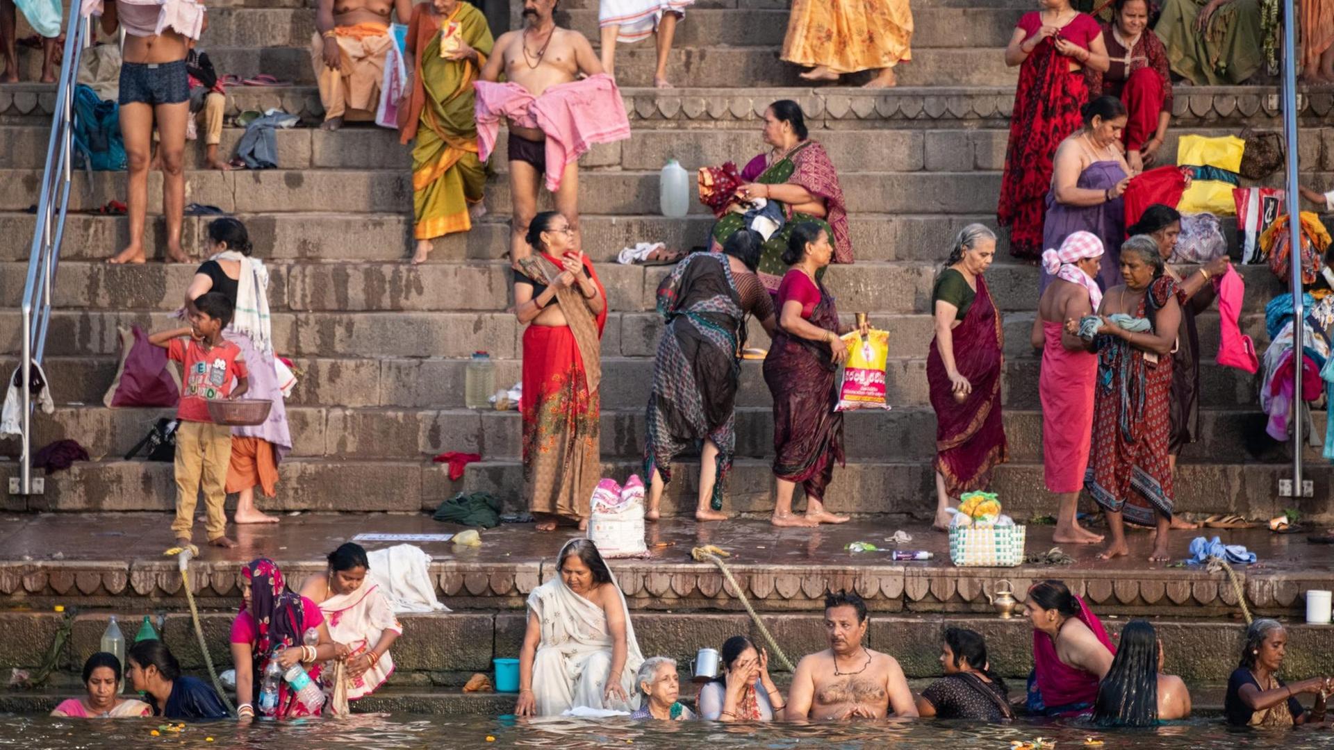 Menschen baden im Wasser des Ganges, eine heilige und reinigende Handlung in der Hindu Religion. Varanasi, Indien, 2018.