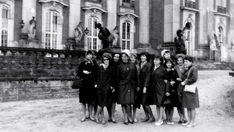 Ein historische Foto auf dem mehrere Frauen auf einer Straße stehen. Ein historische Foto auf dem mehrere Frauen auf einer Straße stehen.