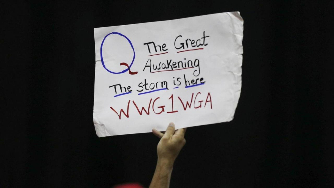 Auf einer Veranstaltung Donald Trumps hält ein Anhänger ein Schild hoch. Darauf ist eine kryptische Botschaft zu lesen: Q The Great Awakening The storm is here WWG1WGA Auf einer Veranstaltung Donald Trumps hält ein Anhänger ein Schild hoch. Darauf ist eine kryptische Botschaft zu lesen: Q The Great Awakening The storm is here WWG1WGA