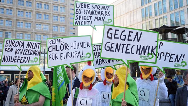 Verkleidete Demonstranten zeigen am 19.05.2014 auf dem Alexanderplatz in Berlin beim Europawahlkampf der SPD Schilder auf denen "Europa nicht den Konzernen ausliefern", "keine Chlor-Hühner für Europa" "Gegen Gentechnik" und "Liebe SPD mit EU-Standards spielt man nicht!" steht.