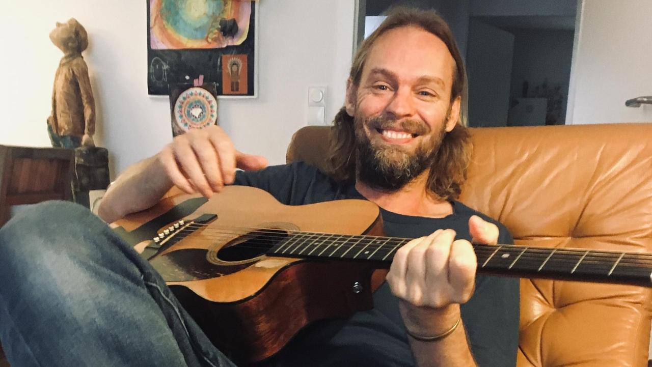 Ingo Pohlmann sitzt mit seiner Gitarre auf dem Schoß auf einem Sessel in seinem Wohnzimmer.