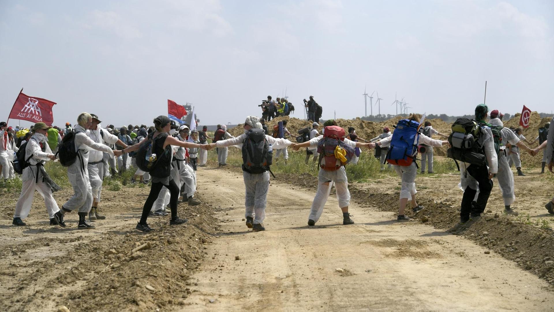 Demonstrantinnen und Demonstranten halten sich an den Händen gefasst und gehen als Kette voran. Demonstrantinnen und Demonstranten halten sich an den Händen gefasst und gehen als Kette voran.