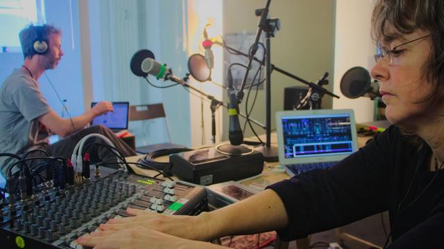 Knut Aufermann und Sarah Washingto sitzen sich im Studio schräg gegenüber und sind an verschiedenen Reglern und Pulten beschäftigt