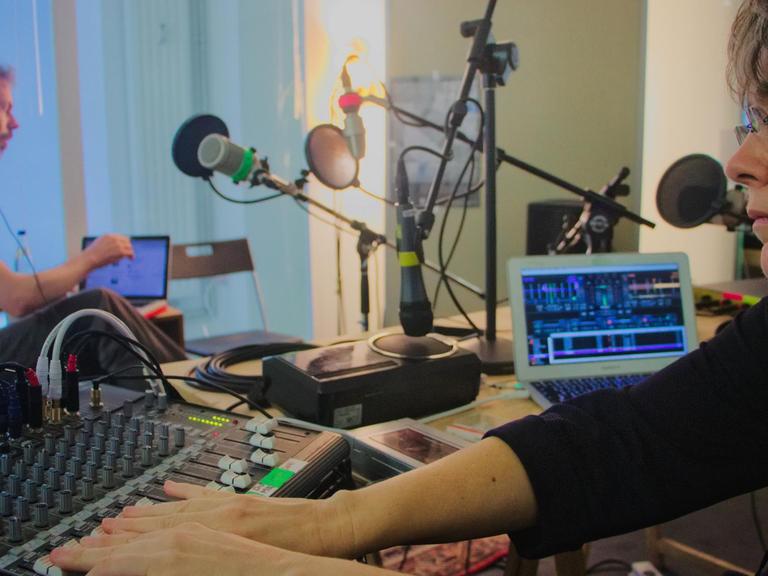 Knut Aufermann und Sarah Washingto sitzen sich im Studio schräg gegenüber und sind an verschiedenen Reglern und Pulten beschäftigt