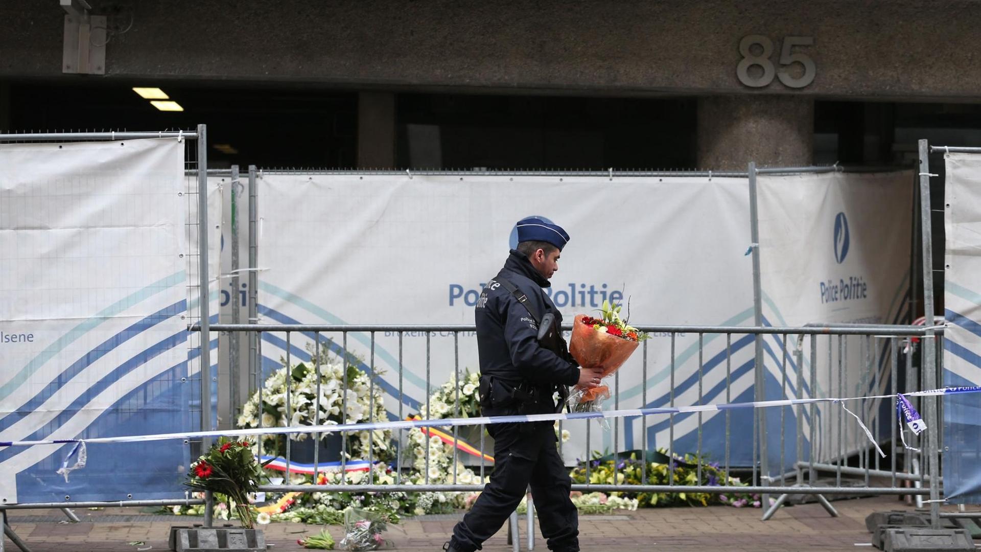Ein Polizist legt vor der Metro-Station Maelbeek Blumen nieder. Ein Polizist legt vor der Metro-Station Maelbeek Blumen nieder.