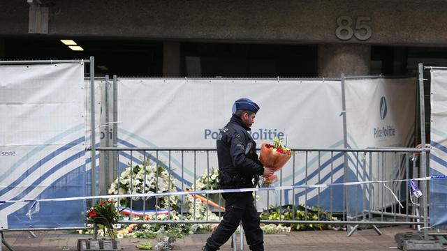 Ein Polizist legt vor der Metro-Station Maelbeek Blumen nieder.