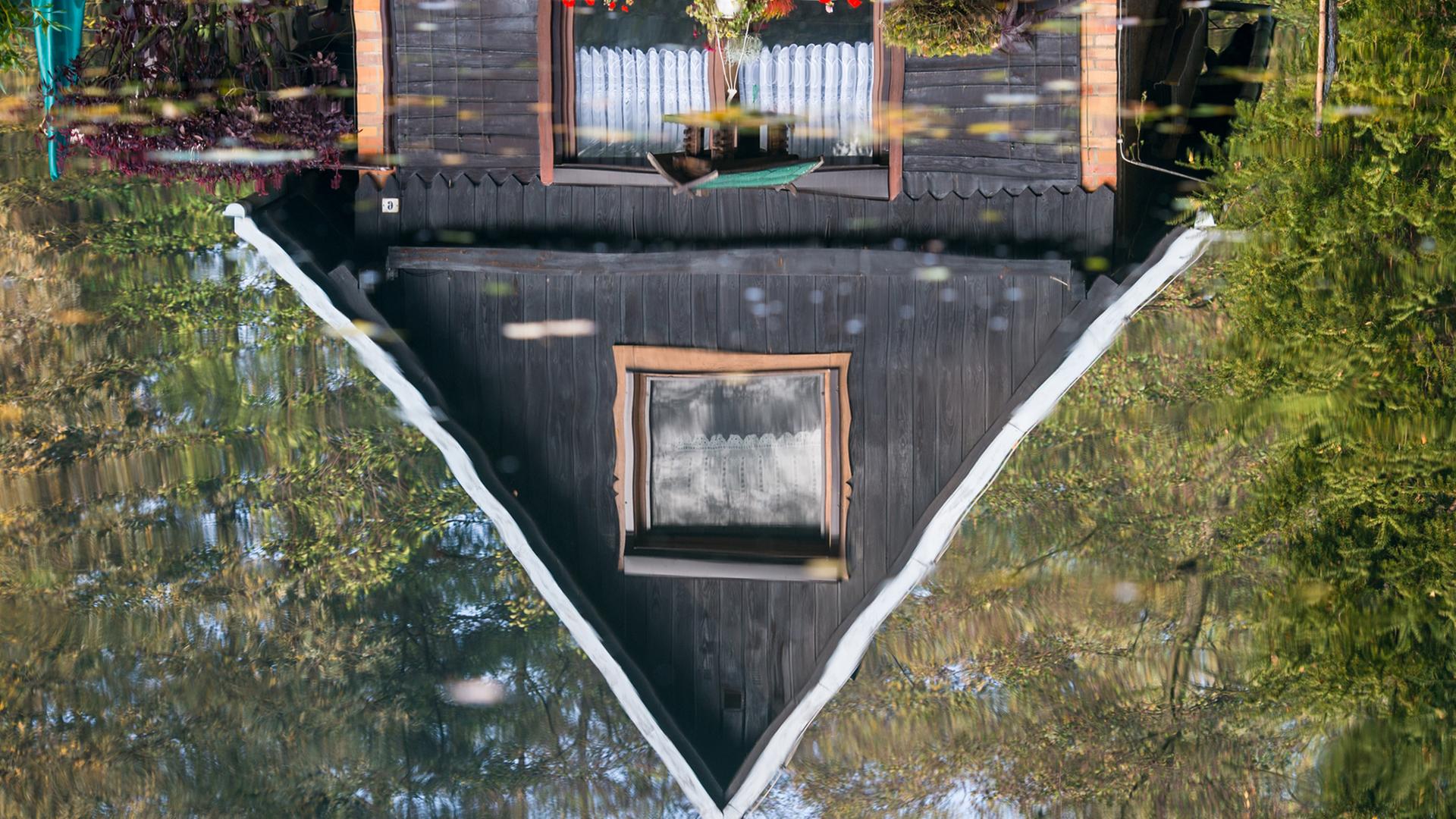 Ein Holzhaus spiegelt sich im Wasser eines Fließes im Spreewaldort Lübbenau (Brandenburg). Ein Holzhaus spiegelt sich im Wasser eines Fließes im Spreewaldort Lübbenau (Brandenburg).