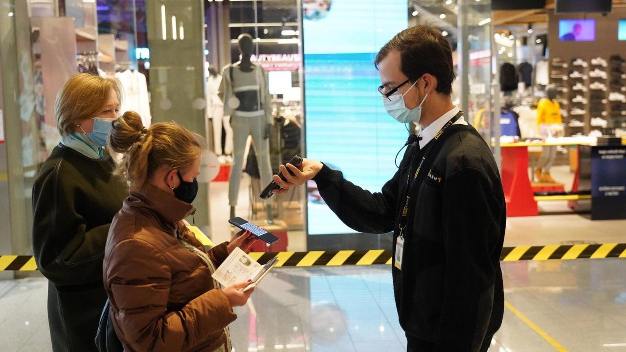 Lettland, Riga: In einem Einkaufszentrum werden die Daten der Corona-Impfungen von zwei Personen überprüft.