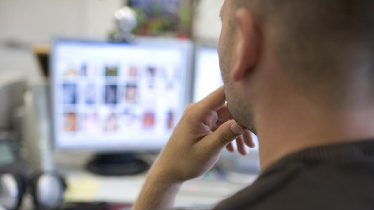Ein Mann sitzt vor einem Computerbildschirm auf dem pornografische Bilder sehen sind.