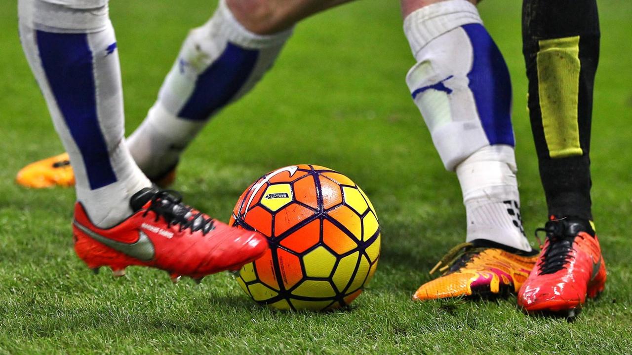 Füße von Fußballspielern und ein bunter Ball Füße von Fußballspielern und ein bunter Ball