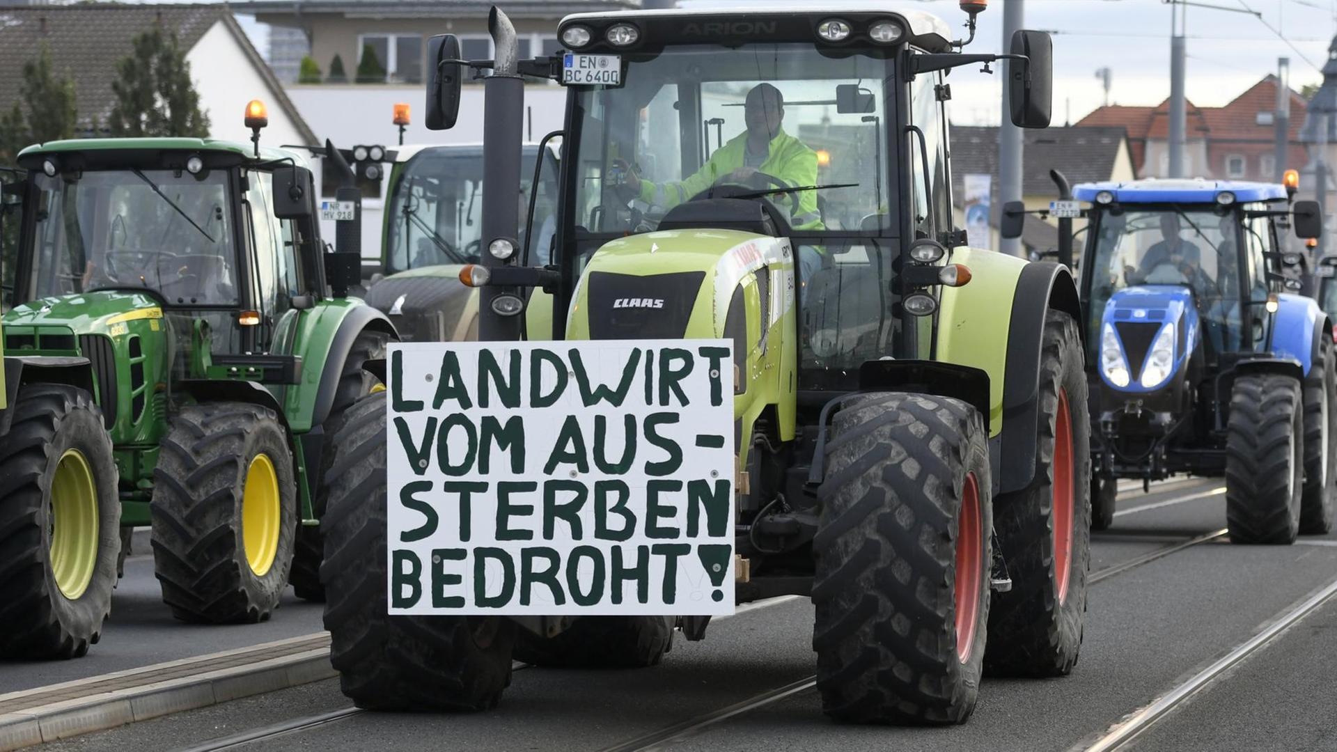 Traktor mit Protestplakat mit der Aufschrift "Landwirt vom Aussterben bedroht".