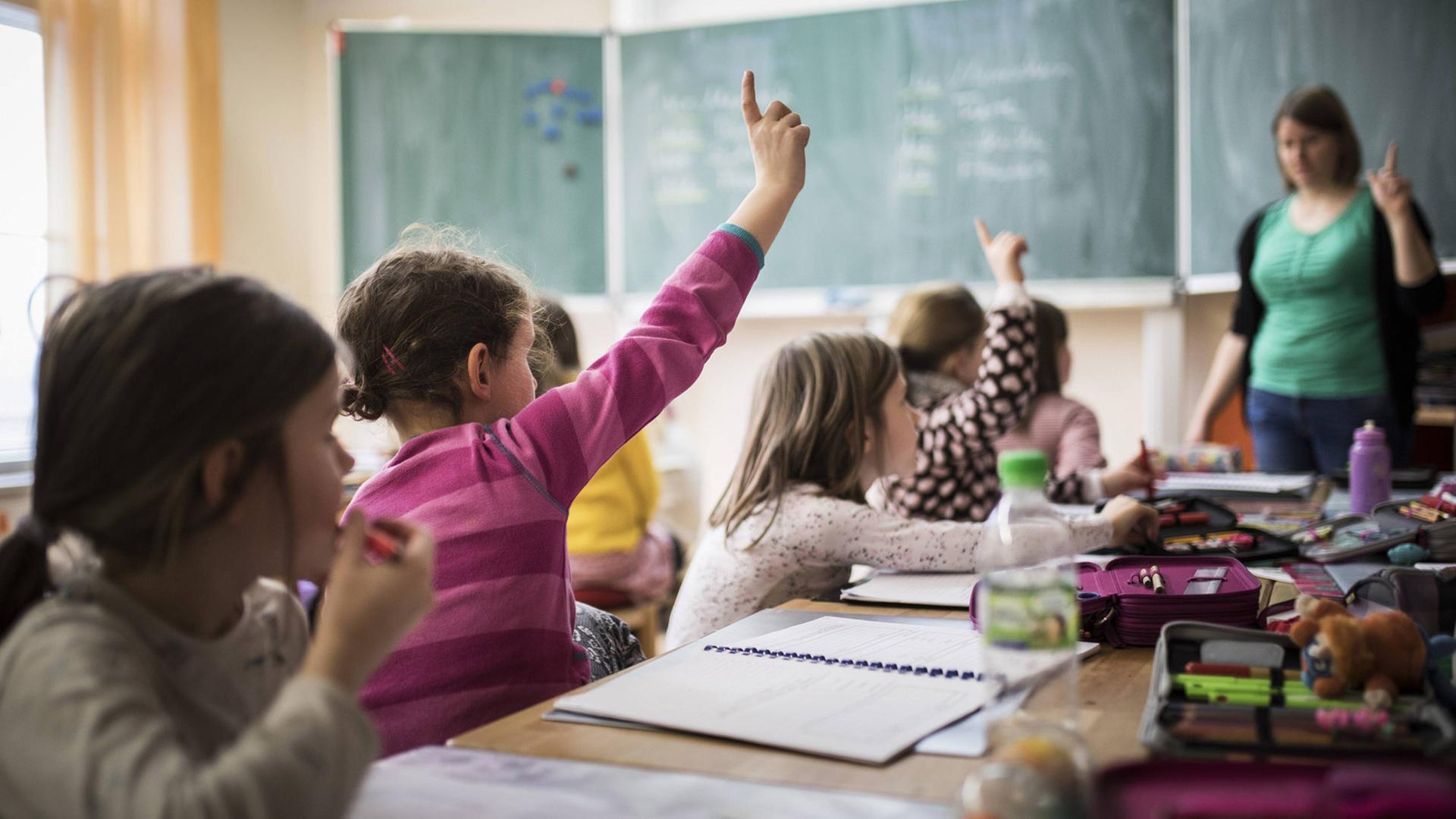 Grundschüler und eine Lehrerin während einer Unterrichtsstunde in einem Klassenzimmer Grundschüler und eine Lehrerin während einer Unterrichtsstunde in einem Klassenzimmer