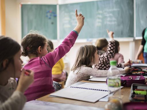Grundschüler und eine Lehrerin während einer Unterrichtsstunde in einem Klassenzimmer