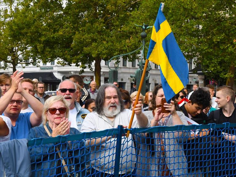 Zuschauer bei einer Veranstaltung der rechtspopulistischen Schweden Demokraten (SD) in Malmö. Ein Mann mit langen grauen Haaren und Bart hält eine schwedische Flagge hoch..