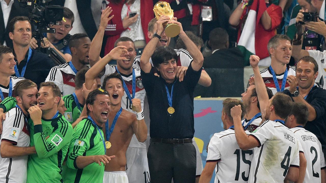 Bundestrainer Joachim Löw hält, umgeben von den deutschen Nationalspielern, den WM-Pokal in die Höhe.
