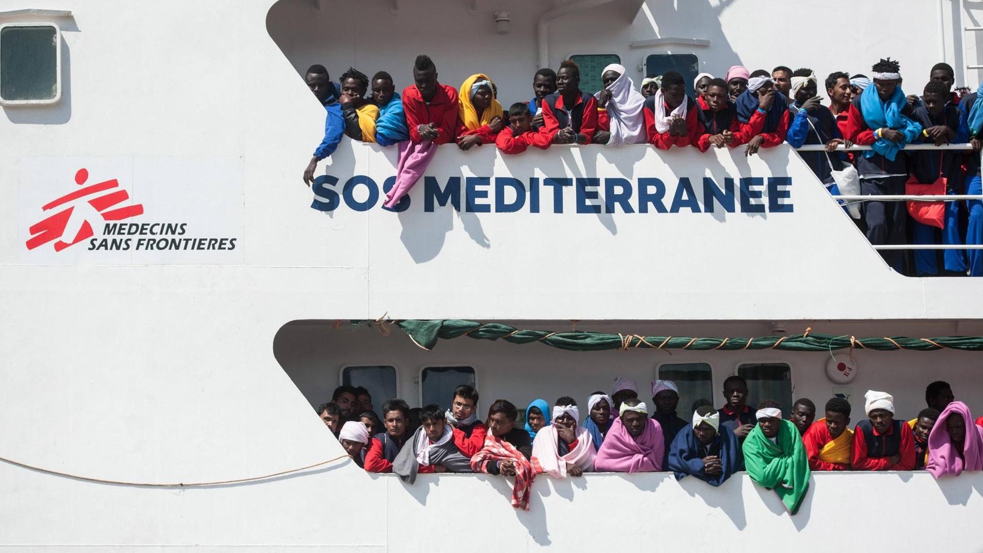 Flüchtlinge stehen an der Reeling des Schiffs Aquarius der Organisation SOS Mediterranee Flüchtlinge stehen an der Reeling des Schiffs Aquarius der Organisation SOS Mediterranee