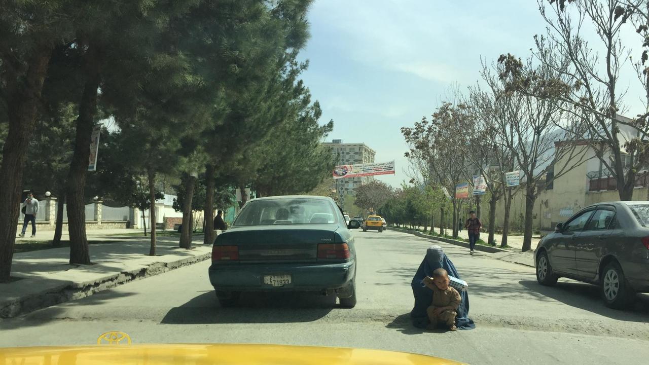 Eine afghanische Frau sitzt mit ihrem Kind mitten auf der Straße in Kabul und bettelt.