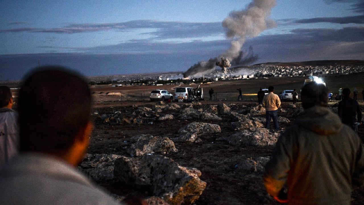 Menschen schauen aus der Ferne auf Kobane - über der Stadt sind Rauchwolken zu sehen. Menschen schauen aus der Ferne auf Kobane - über der Stadt sind Rauchwolken zu sehen.