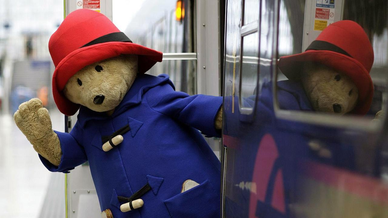 Ankunft von Bär Paddington in der Londoner Paddington Station. Der Bär lehnt aus dem Zug und winkt. Ankunft von Bär Paddington in der Londoner Paddington Station. Der Bär lehnt aus dem Zug und winkt.