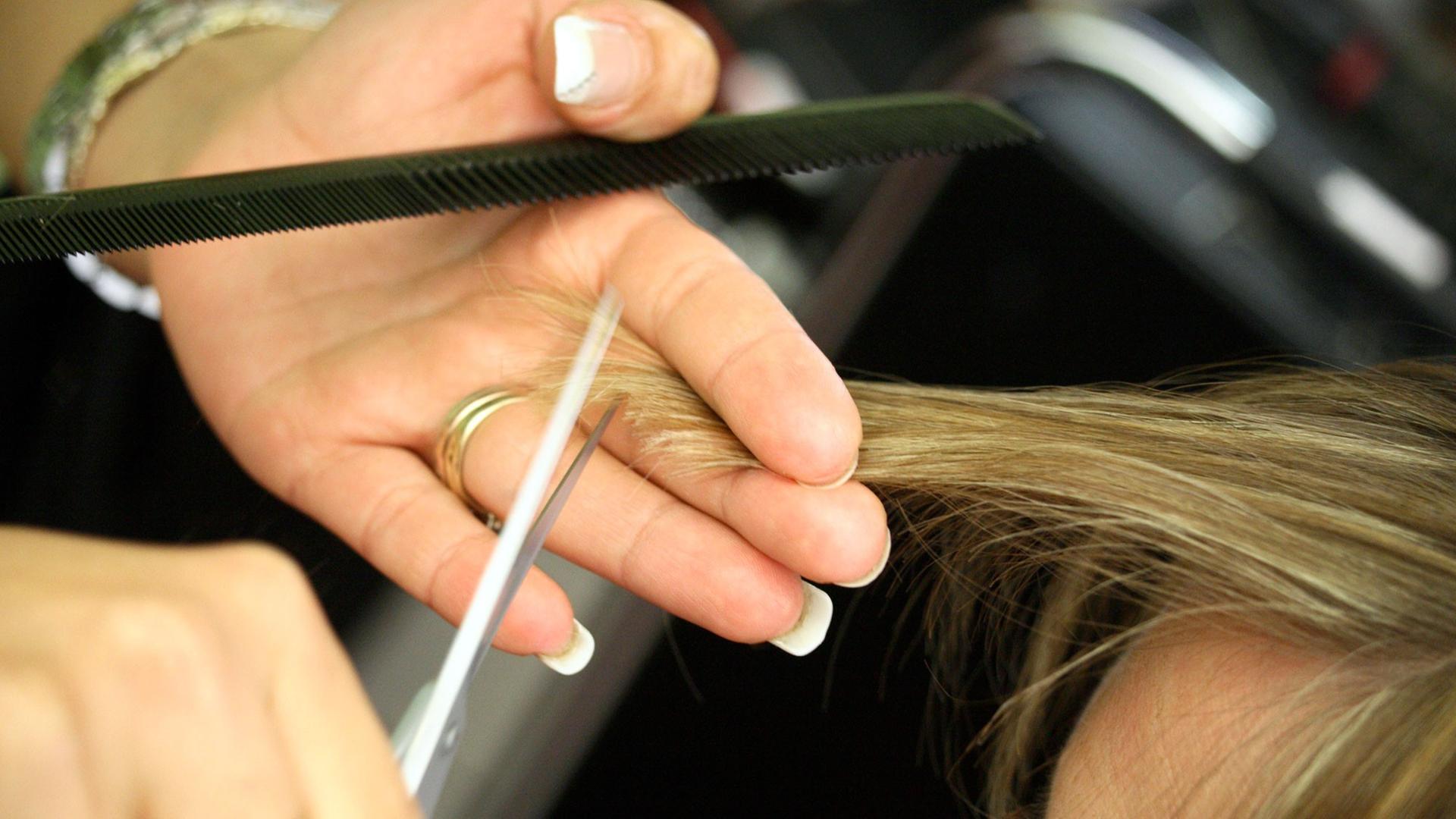 Eine Friseurin schneidet einem Kunden die Haare. Eine Friseurin schneidet einem Kunden die Haare.